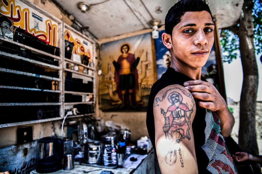 A young Copt boy proudly shows his tattoo outside the church in Cairo